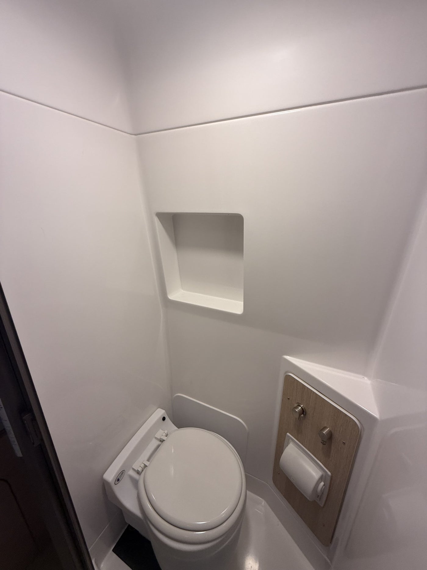 Compact, pristine all-white bathroom inside an RV rental, featuring a modern toilet and built-in shelf. — photo 13