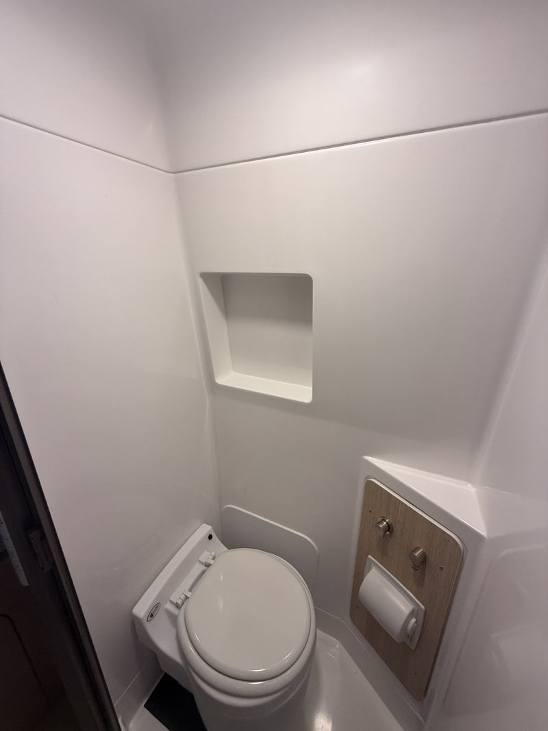Compact, pristine all-white bathroom inside an RV rental, featuring a modern toilet and built-in shelf. — photo 13