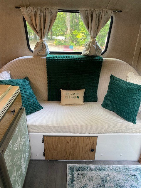 Cozy RV rental interior with comfy seating, green decor, Wisconsin-themed pillow, and scenic window view. — photo 5