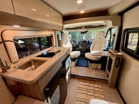 Step inside this modern RV rental! Features a full kitchen, living area, and swivel front seats for a comfortable journey.