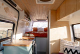 Spacious and bright RV rental interior featuring a modern kitchen with a sink & stove, and a cozy bed, perfect for van life adventures.