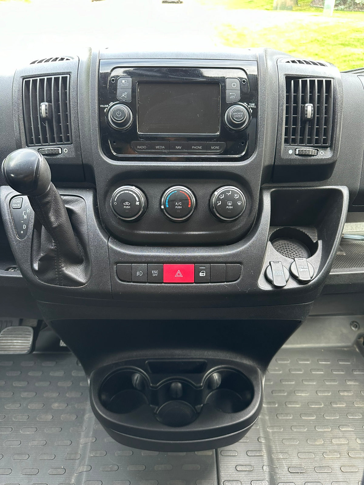 Dashboard of an RV rental showing controls, gear shift, infotainment, and charging ports. Perfect for your next trip! — photo 17