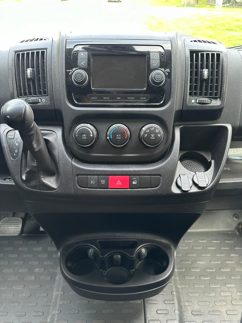 Dashboard of an RV rental showing controls, gear shift, infotainment, and charging ports. Perfect for your next trip! — photo 17