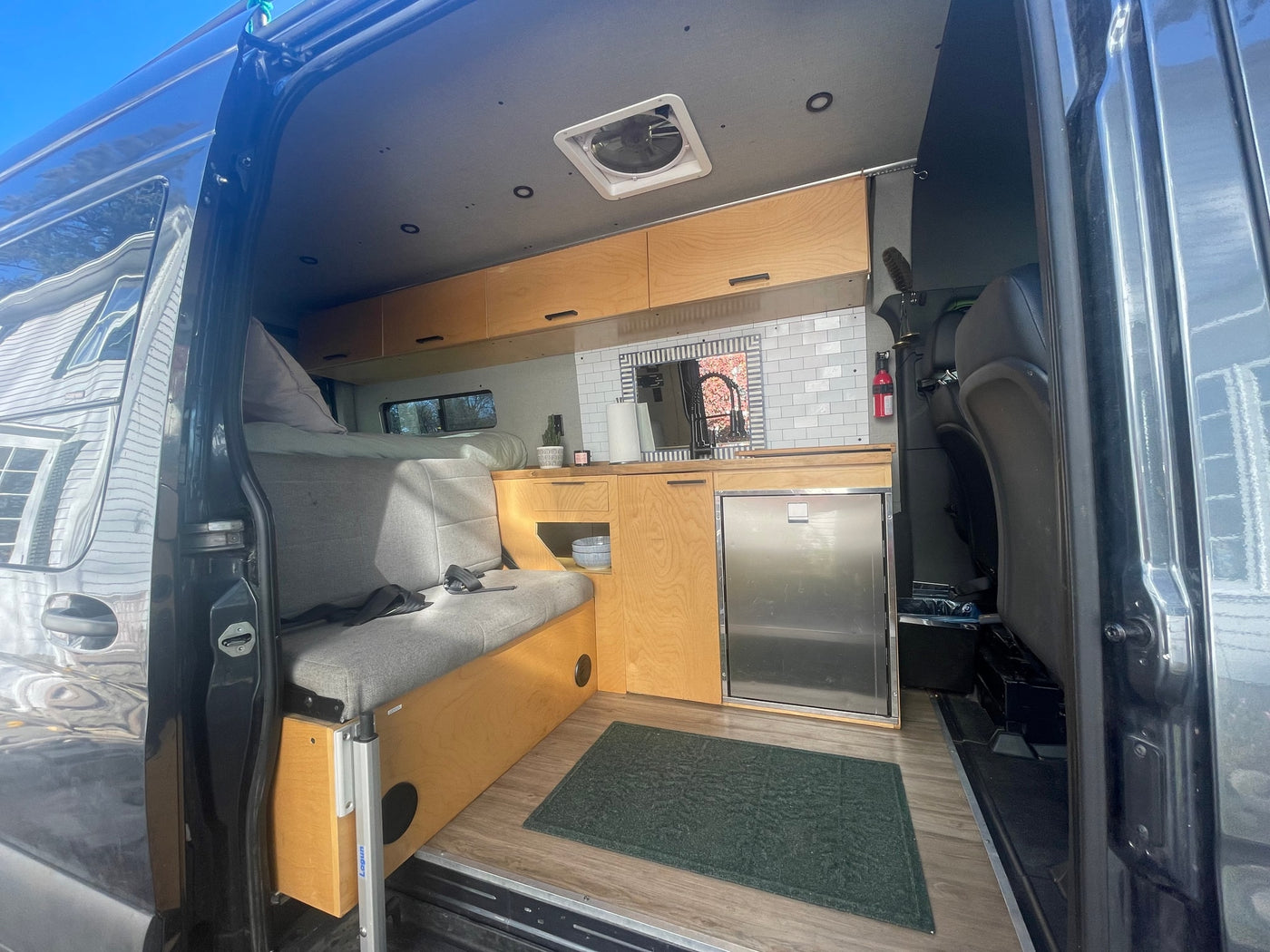  and a comfortable sleeping area.|Dark grey RV rental Sprinter van parked on a dirt road in a tall — photo 3