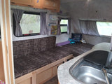 Inside a functional RV rental: cozy seating converts to a bed, with a compact kitchen and storage for comfortable travel.
