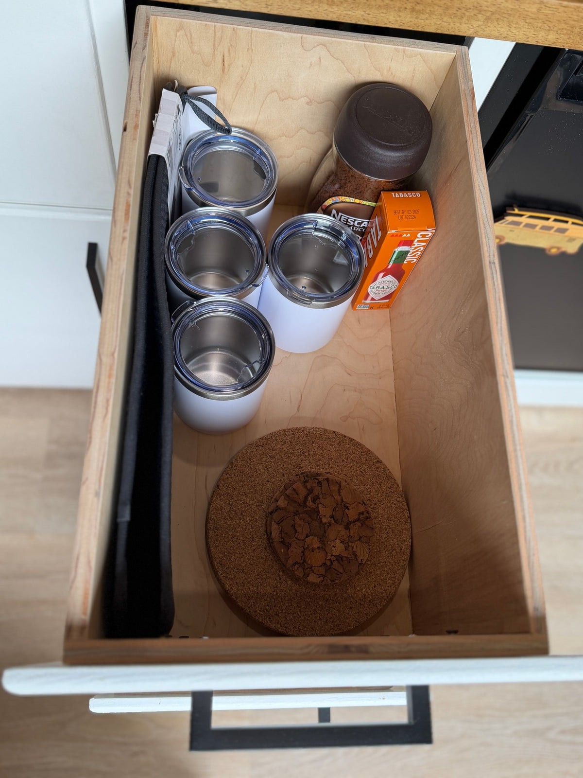 Inside an RV rental kitchen drawer: insulated tumblers, Nescafé, Tabasco, and cork trivets for on-the-go meals. — photo 15