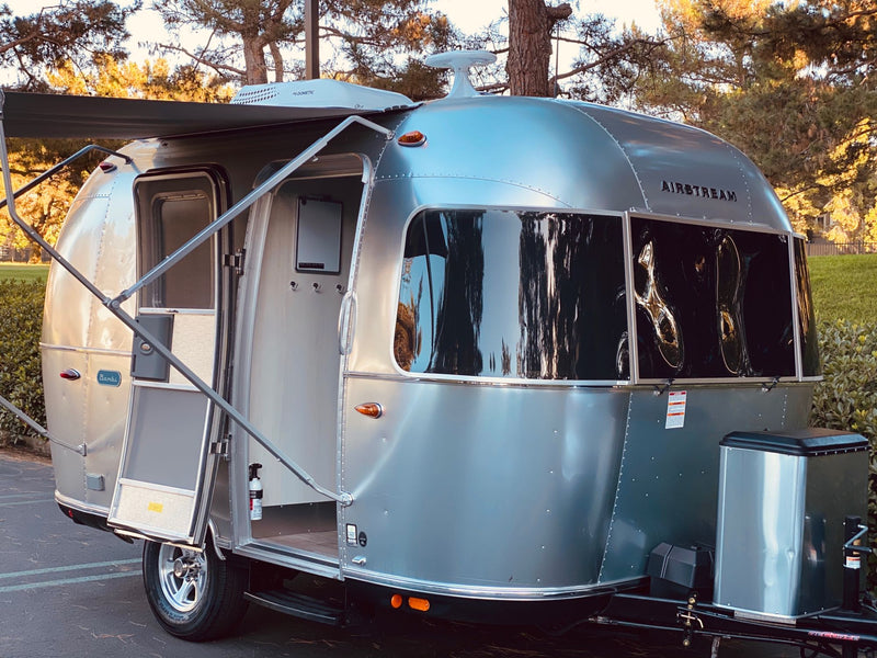  with a picnic table and cooler ready for camp.|A sleek silver Airstream travel trailer (an RV rental) towed by an Infiniti SUV — photo 3