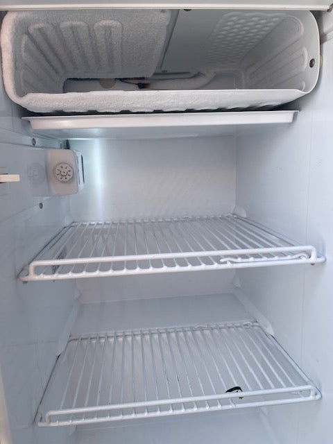 RV rental freezer showing significant frost on coils and evaporator, with wire shelves. Needs defrosting for optimal use.