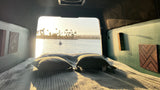 Cozy RV rental bed with a stunning water view. Enjoy serene sunsets, sailboats, and palm trees from your van life retreat.
