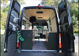 Inside a black RV rental van: custom wood ceiling, sleek black cabinets, and organized storage for adventures.