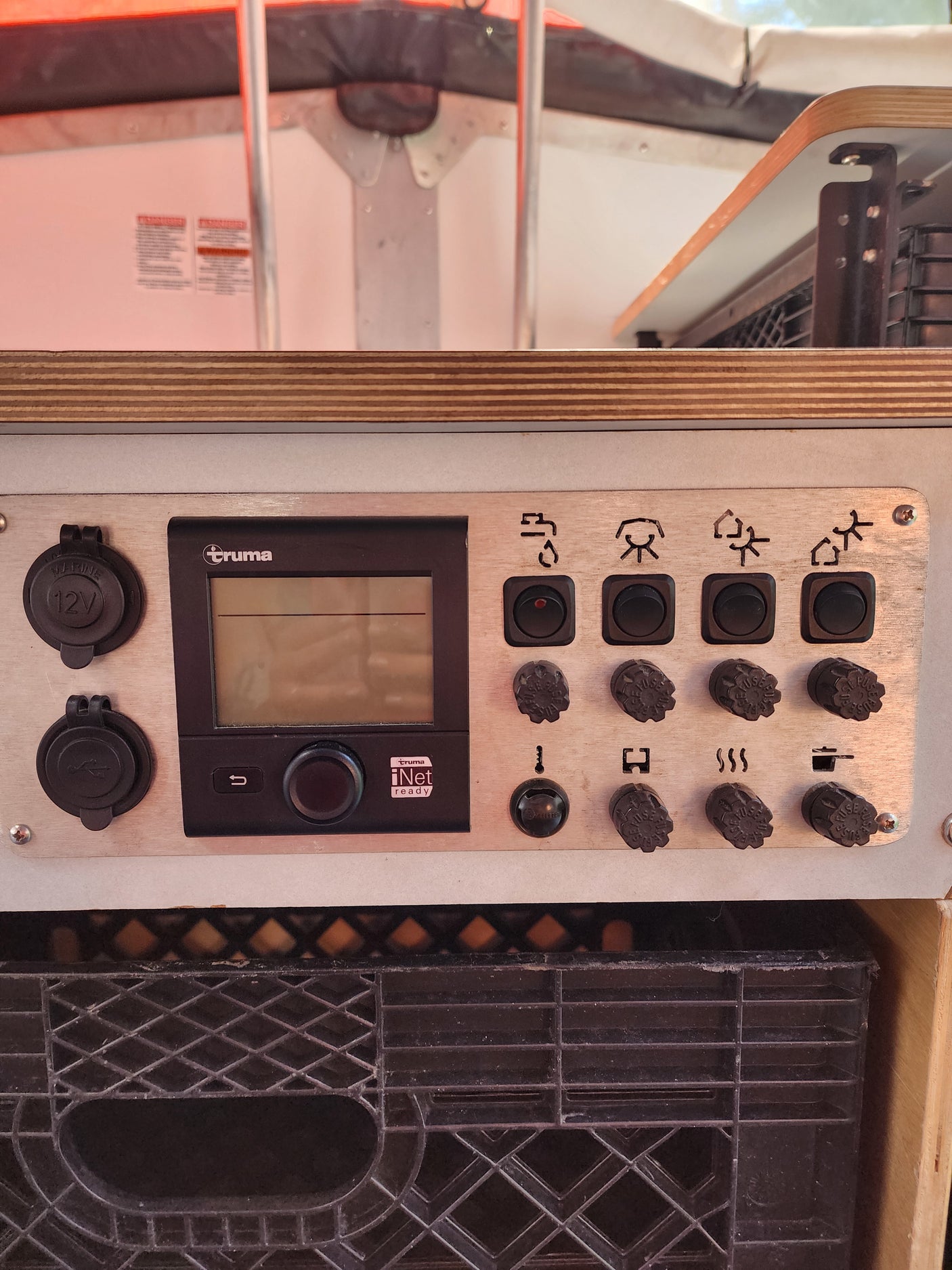 RV rental control panel detail: Truma system, 12V/USB power outlets, and multiple function switches on a silver panel.