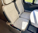 RV rental: Cream quilted seating and a table in a bright, modern camper van interior.