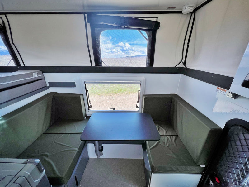 This RV rental offers a spacious pop-up camper interior with a cozy dinette, sleeping area, and panoramic views. — photo 10