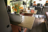 Cozy RV rental interior with a toaster, fresh flowers, and coffee setup on wooden tables, perfect for a road trip.