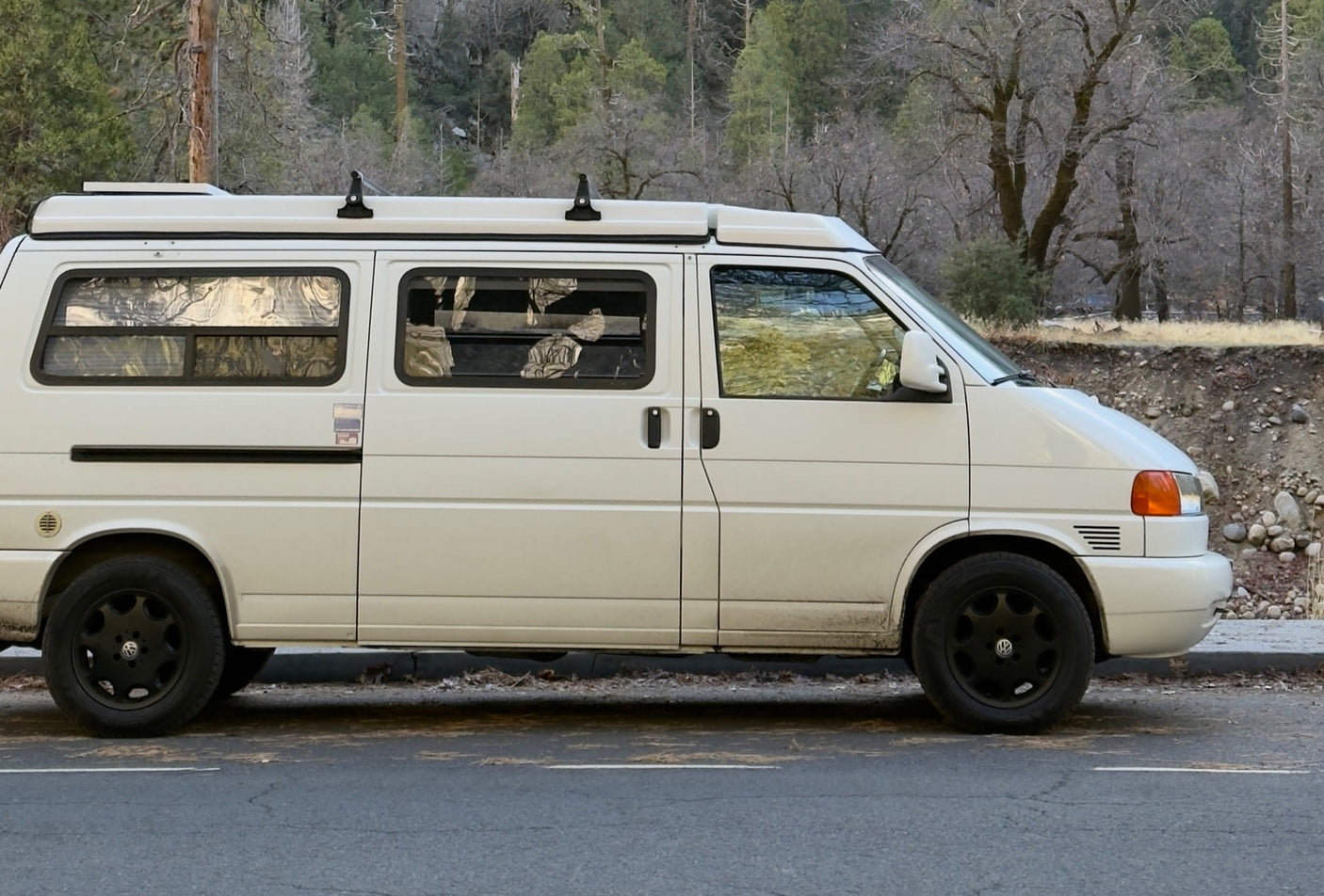 White RV rental campervan parked roadside, ready for adventure in a tranquil winter forest setting.