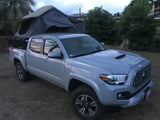 This grey Tacoma pickup with a rooftop tent makes for a unique RV rental, perfect for outdoor adventures.