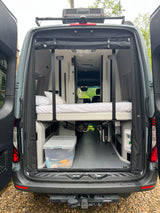 Explore a modern RV rental: open back doors reveal a comfortable elevated bed and versatile storage.