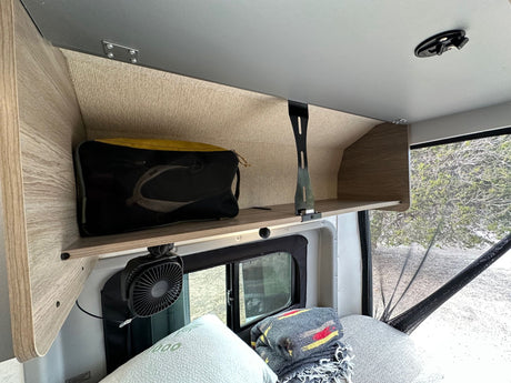 Inside an RV rental: cozy overhead storage, fan, window with screen. Perfect for comfortable van life adventures.