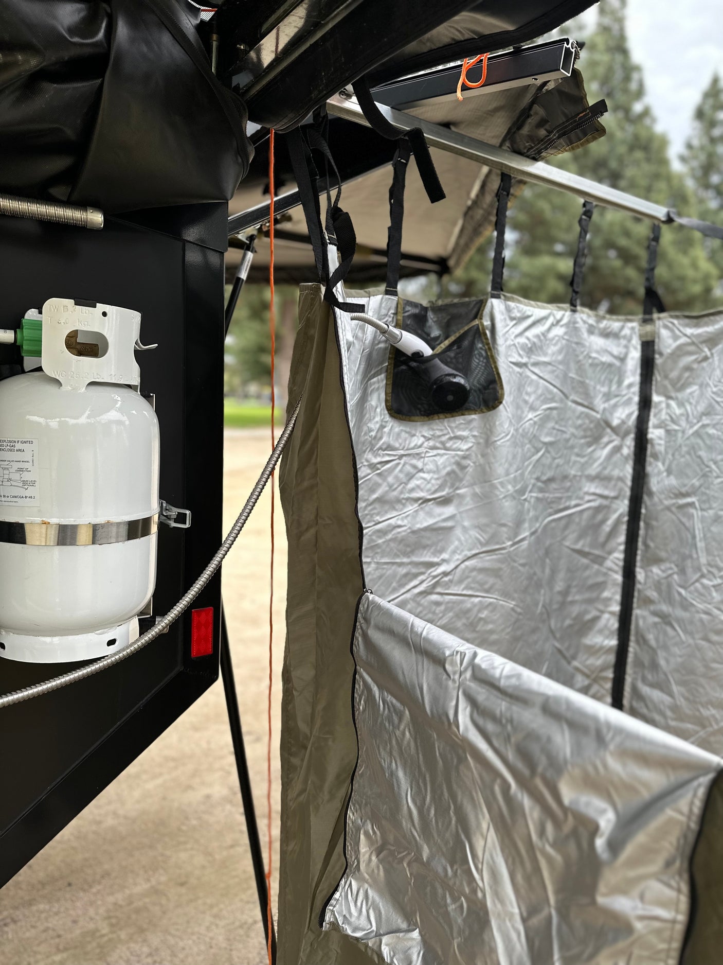 Outdoor shower and propane tank setup for an RV rental, offering convenient amenities for camping trips.